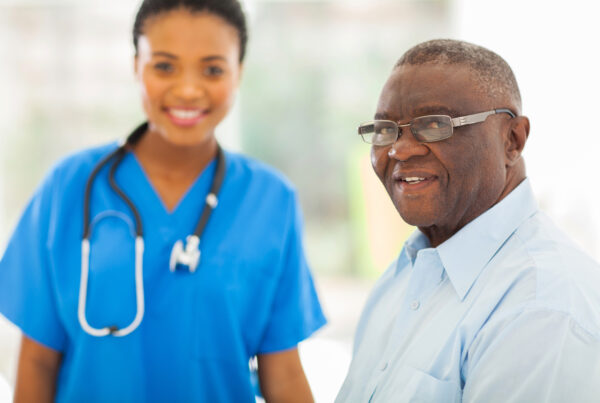 A nurse standing next to an elderly man.